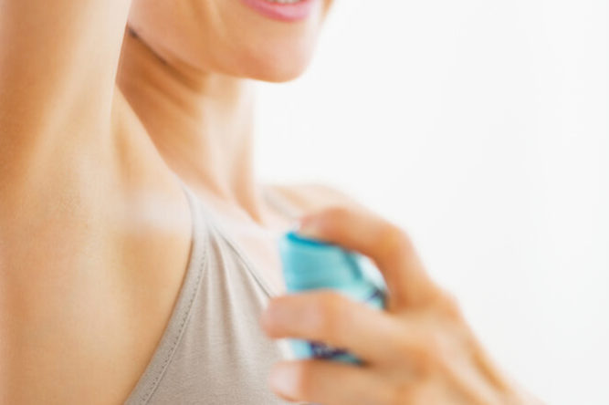 Woman spraying deodorant to her underarm